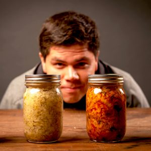 man looking at jars of fermented vegetables