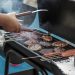 person cooking food items on a barbecue grill