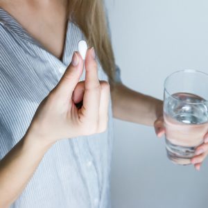 woman taking a pill with a glass of water