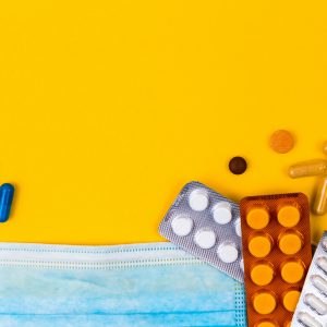 an assortment of medications, a medical faces mask and thermometer