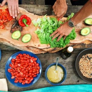 two people chopping a bunch of vegetables