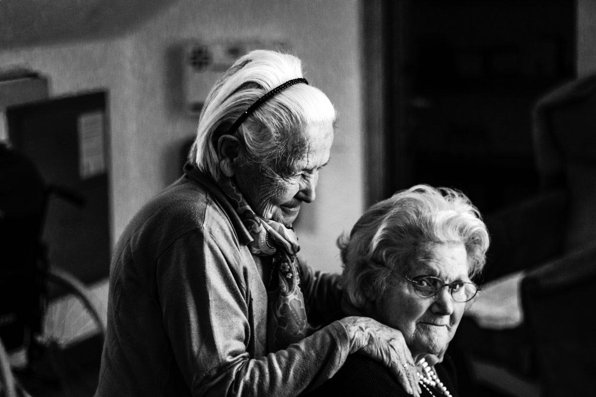 two old women standing near each other looking at the camera