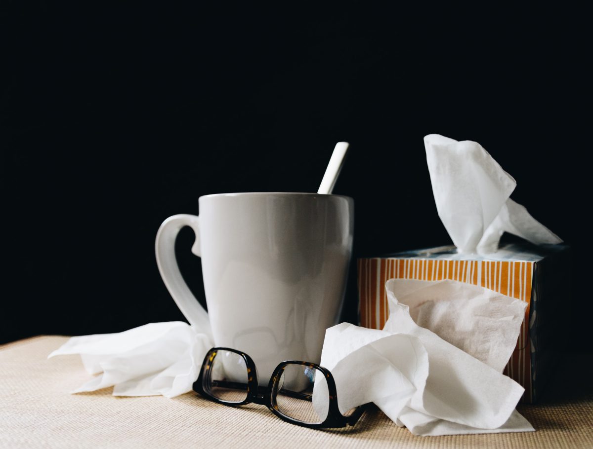 mug, glasses and nose tissues on a table