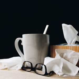 mug, glasses and nose tissues on a table