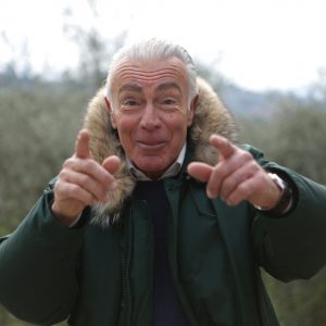 old man smiling and pointing enthusiastically at the camera