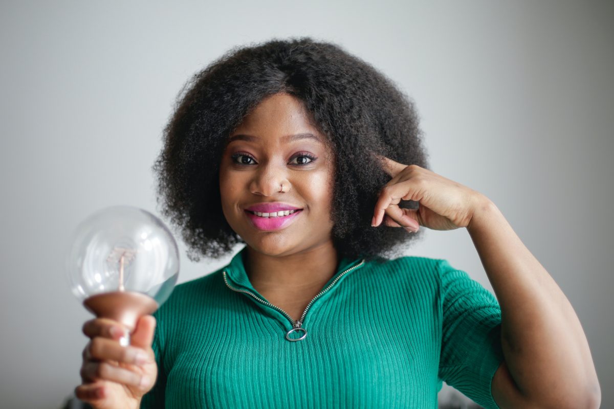 woman pointing at her head and holding a light bulb