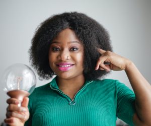 woman pointing at her head and holding a light bulb