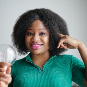 woman pointing at her head and holding a light bulb