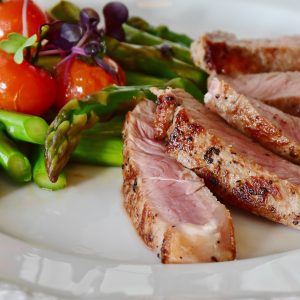 a white plate with steak fillets and asparagus on it