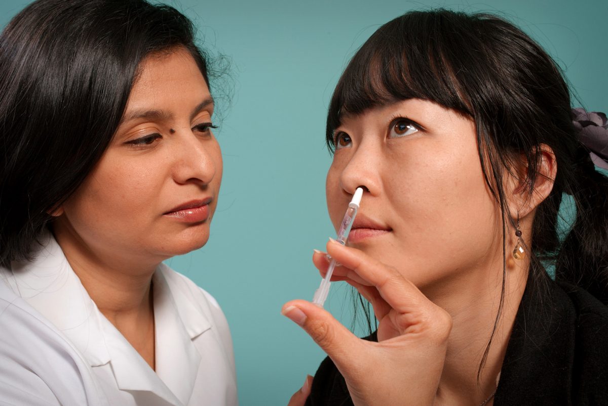 woman administering a nasal medicine to a patient