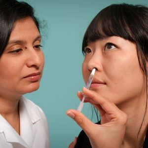 woman administering a nasal medicine to a patient