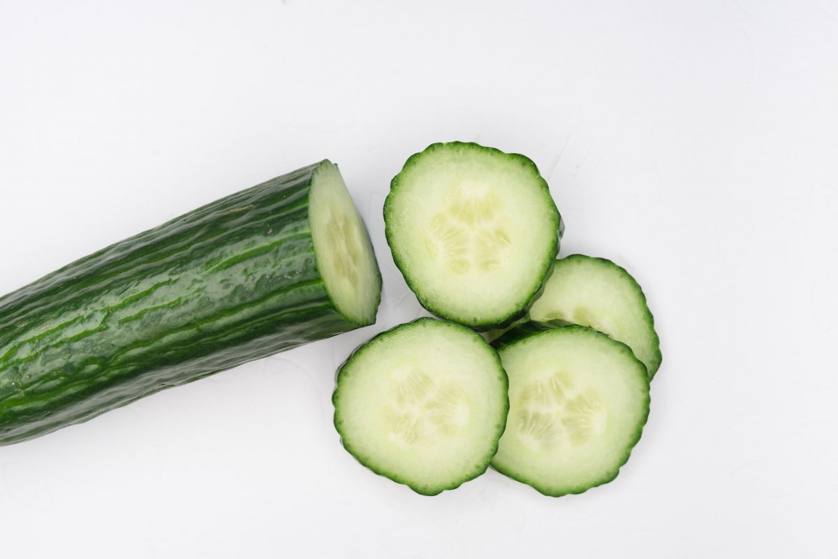 cucumber and cucumber slices against a white backdrop