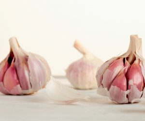 3 garlic heads on a counter against a white backdrop