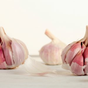 3 garlic heads on a counter against a white backdrop