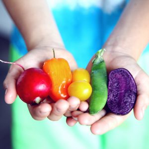 woman holding brightly colored vegetables