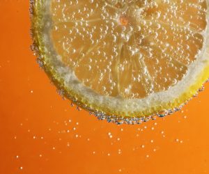 lemon slice in fizzy water with an orange background