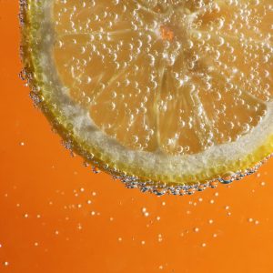 lemon slice in fizzy water with an orange background