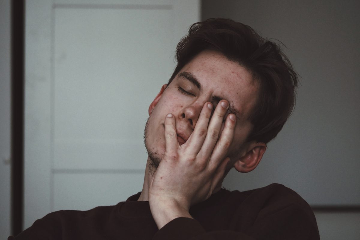 man looking tired with hand on his face