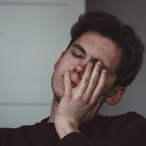 man looking tired with hand on his face