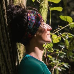 woman leaning against a tree with eyes closed