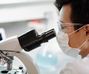 man looking through microscope in a medical lab