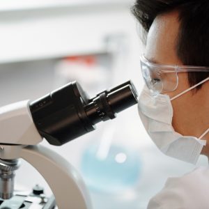 man looking through microscope in a medical lab