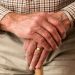 old man's hands resting on top of a walking cane