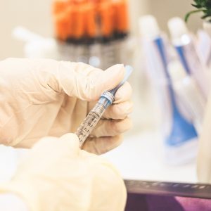 person in a medical lab filling a syringe