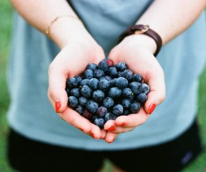 person holding blueberries in their cupped hands