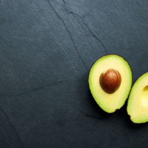 an avocado sliced in half against a black backdrop