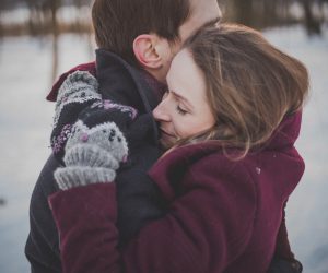 man and woman hugging while standing in snow