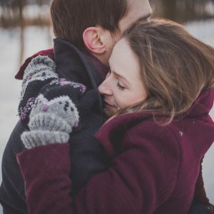 man and woman hugging while standing in snow